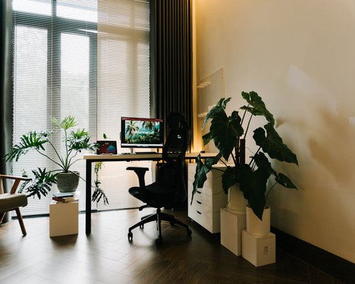 A modern desk setup near a large window with soft sunlight entering laterally